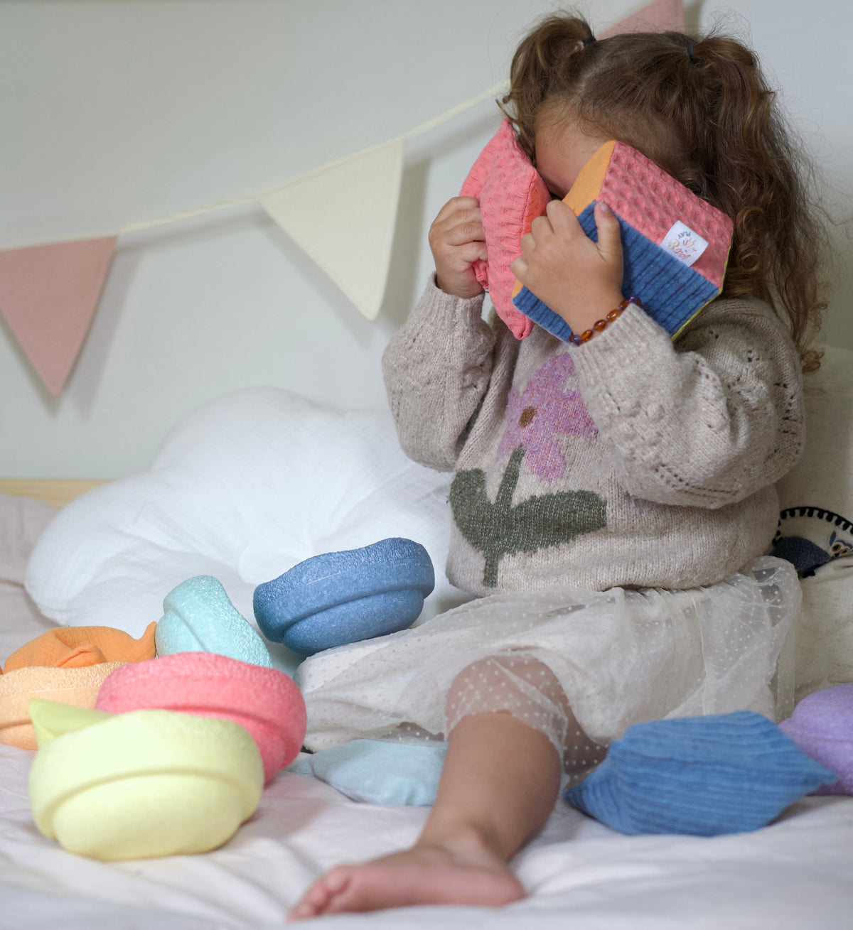 Kind verstopt zich achter de Pit and Play Dobbelstein Pastel en een pittenzakje tijdens vrij spel