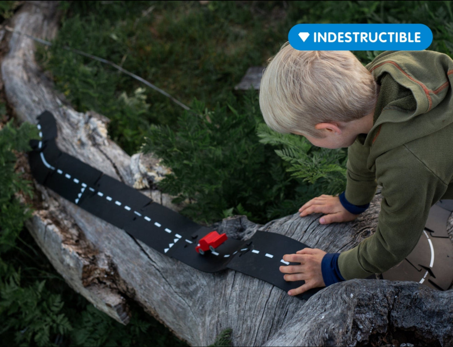 Kind speelt buiten met Waytoplay Expressway autobaan op natuurlijke boomstammen